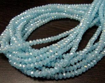 May include: A strand of light blue faceted glass beads. The beads are small and have a slightly iridescent finish.