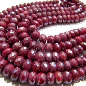 May include: A strand of deep red ruby beads, each bead is faceted and oval shaped.