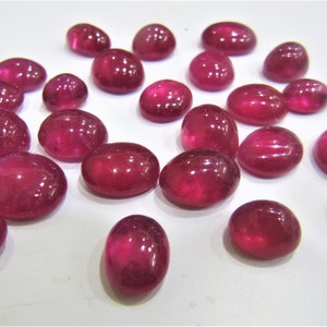 Peut inclure: Une collection de 20 pierres précieuses de rubis de forme ovale, taillées en cabochon. Les rubis sont d'une couleur rouge foncé et riche et ont une finition lisse et polie.