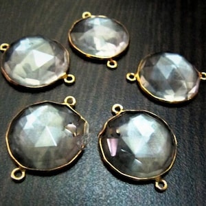 Puede incluir: Cinco cuentas redondas de cristal transparente con bucles de conexión de metal dorado. Las cuentas tienen un diseño facetado y miden aproximadamente 2,5 cm de diámetro.