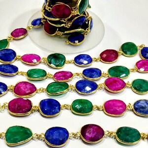 May include: A strand of gemstone beads with gold connectors. The beads are oval shaped and come in shades of blue, green, and pink.