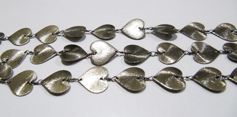May include: A silver necklace with a chain made of small, connected heart-shaped charms.