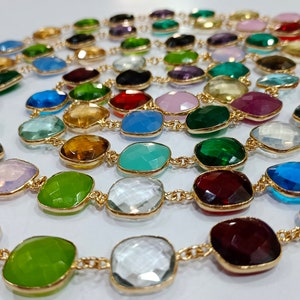 May include: A gold chain necklace featuring faceted gemstone beads in a variety of colours, including pink, green, blue, red, and clear. The beads are all roughly the same size and shape, and are strung on a fine gold chain.