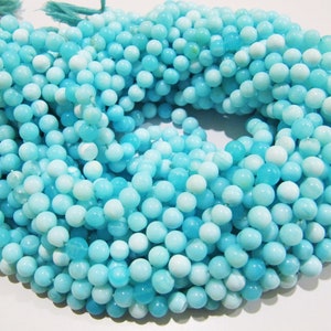 May include: A strand of round, turquoise blue and white opal beads. The beads are smooth and have a slight sheen.