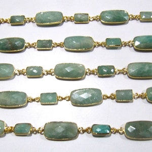 May include: Close-up of several strands of jewelry featuring rectangular and square-cut, light green gemstones. The gemstones are set in gold-colored metal and connected by delicate gold chains. The design is symmetrical and elegant.