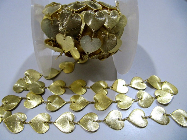 May include: A gold heart-shaped chain trim with a metallic finish. The chain is made of individual heart-shaped links connected by small metal rings.