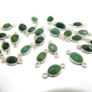 May include: A collection of oval-shaped green gemstone connector charms with silver-toned metal accents. Each charm has two loops for attaching to jewelry.