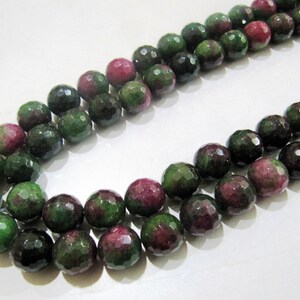 May include: A strand of green and pink gemstone beads. The beads are faceted and have a round shape.