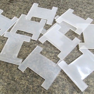 May include: A pile of ten clear plastic bobbins for thread.