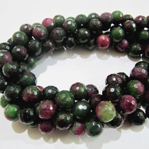 May include: A strand of faceted green and pink gemstone beads. The beads are round and have a polished finish.