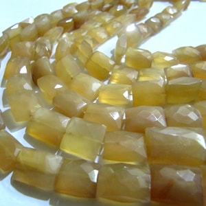 Puede incluir: Una hebra de cuentas de piedras preciosas de color amarillo claro, cada cuenta está facetada y tiene forma rectangular.