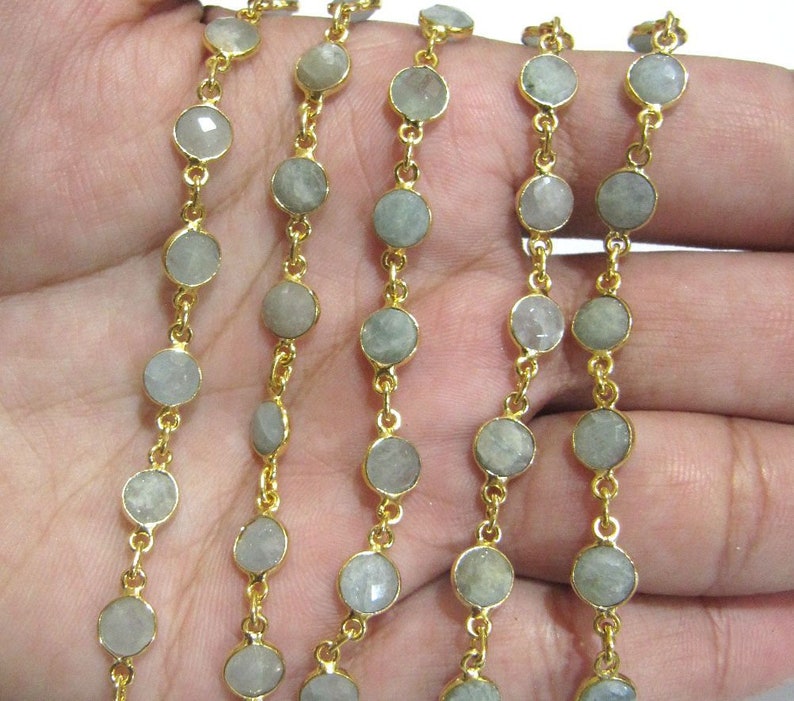 Puede incluir: Una cadena de oro con cuentas redondas de piedra preciosa gris claro. La cadena est&aacute; hecha de metal chapado en oro y las cuentas tienen un di&aacute;metro aproximado de 6 mm.