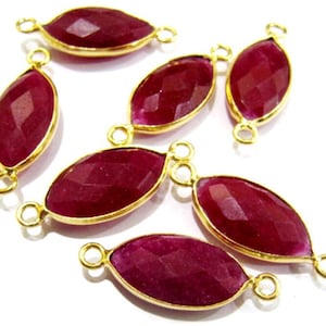 May include: Seven oval-shaped gemstone connectors with gold-toned metal accents. The gemstones are a deep red color and have a faceted finish.