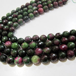 May include: A strand of faceted green and pink gemstone beads. The beads are round and have a polished finish.