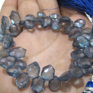 May include: A strand of faceted blue gemstone beads. The beads are irregularly shaped and have a slightly iridescent finish.
