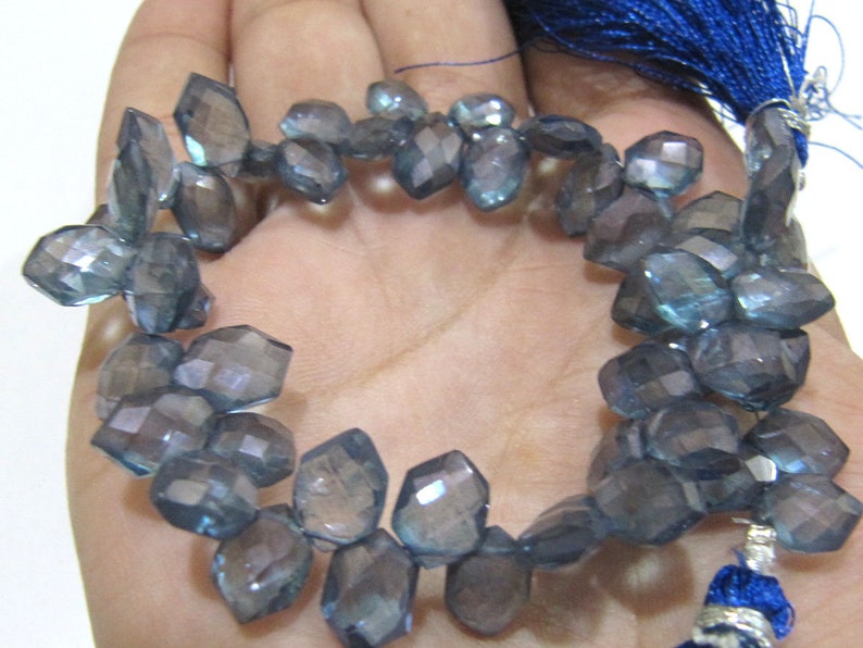 May include: A strand of faceted blue gemstone beads. The beads are irregularly shaped and have a slightly iridescent finish.