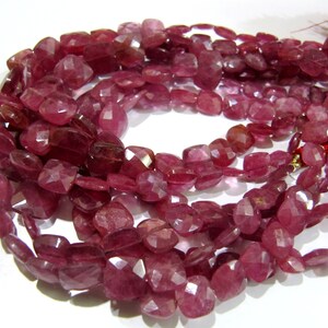 May include: A strand of pink gemstone beads with a faceted, cushion-shaped cut. The beads are strung on a clear cord and have a natural, slightly translucent appearance.