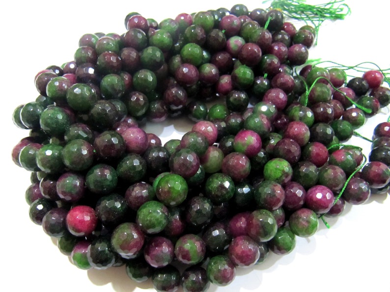 May include: A strand of faceted gemstone beads in shades of green and pink. The beads are round and have a smooth, polished finish.