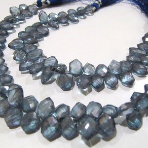 May include: A strand of faceted blue topaz beads, each bead is a unique, irregular shape. The beads are strung on a cord with a blue tassel at each end.