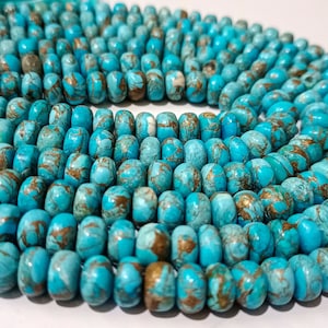 May include: A strand of turquoise blue beads with gold flecks. The beads are round and have a smooth, polished finish.