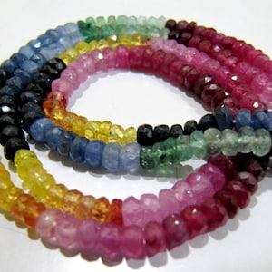 May include: A strand of faceted gemstone beads in a rainbow of colours, including blue, yellow, green, pink, and red. The beads are strung on a clear thread and are arranged in a circular pattern.