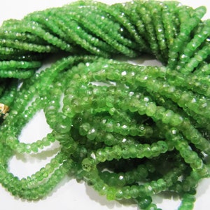 May include: A strand of green gemstone beads, likely peridot, with a faceted, slightly irregular shape. The beads are strung on a thin thread and are approximately 3mm in diameter.