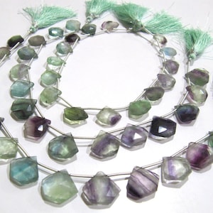 May include: A strand of faceted fluorite beads in shades of green, purple, and blue. The beads are strung on silver wire and have a faceted, teardrop shape. The beads are approximately 10mm in size.
