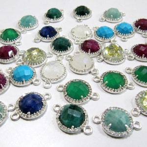 May include: Assortment of gemstone connector charms with silver settings and a diamond-like halo. The gemstones include amethyst, ruby, turquoise, sapphire, moonstone, citrine, and green onyx.