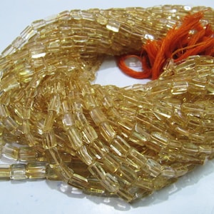 Puede incluir: Una hebra de cuentas de citrino amarillo dorado, cada cuenta es facetada y de forma rectangular. Las cuentas están enhebradas en un cordón fino y están atadas juntas con un borla.