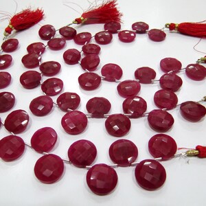 Peut inclure: Un collier de perles de pierres précieuses rouges avec des perles rondes facettées. Les perles sont enfilées sur un fil d'argent et ont un pompon à chaque extrémité.