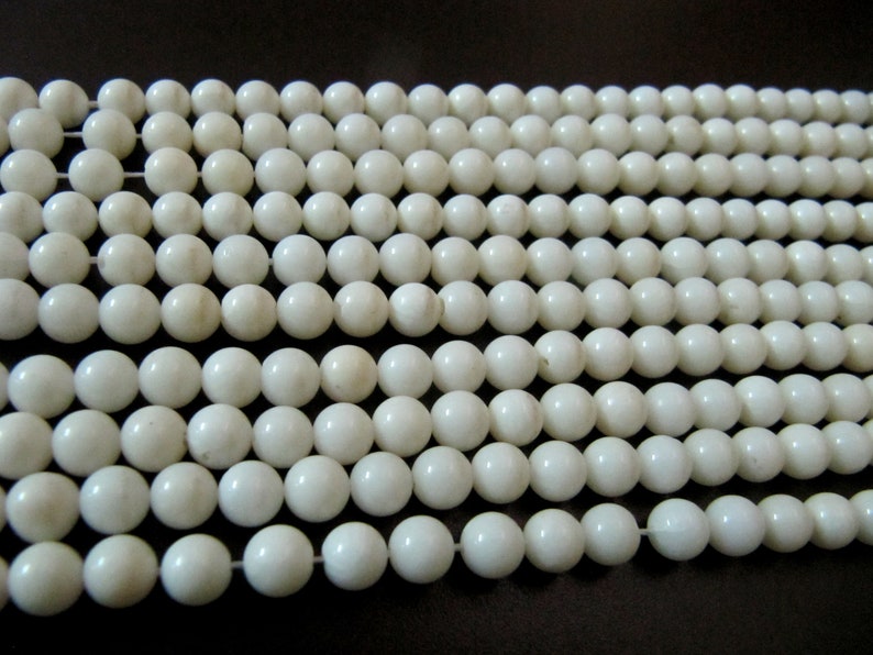 May include: A strand of white round beads, made of natural shell, for jewelry making.