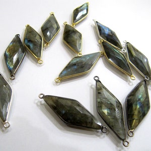Op de afbeelding: Een groep van 12 edelsteen connector charms met goudkleurige metalen accenten. Elke charm is een gefacetteerde, diamantvormige labradorite steen met een donkergrijze, blauwe en groene kleur.