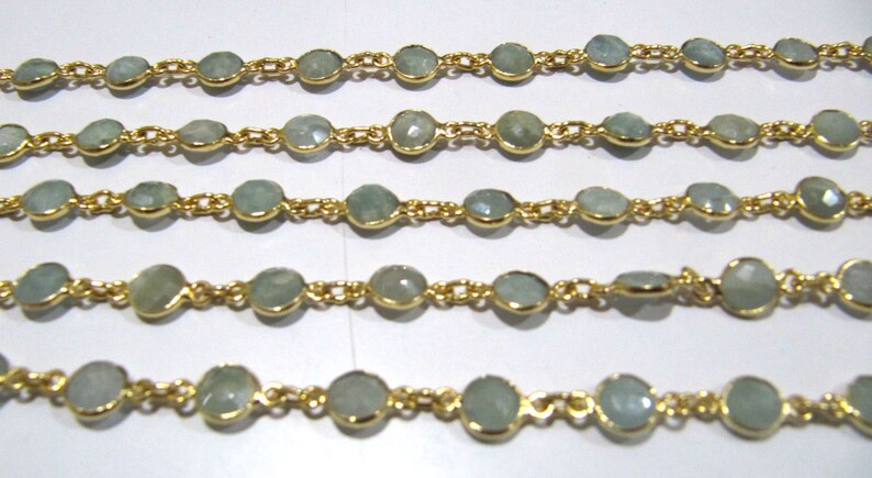 Puede incluir: Una cadena de oro con cuentas de piedras preciosas de color azul claro. La cadena est&aacute; hecha de peque&ntilde;as piezas de metal unidas. Las cuentas son redondas y tienen una apariencia ligeramente facetada.