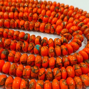 May include: A strand of orange and black gemstone beads. The beads are round and have a speckled pattern.