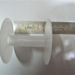 May include: A white plastic spool with a center hole, measuring approximately 6 inches in diameter.