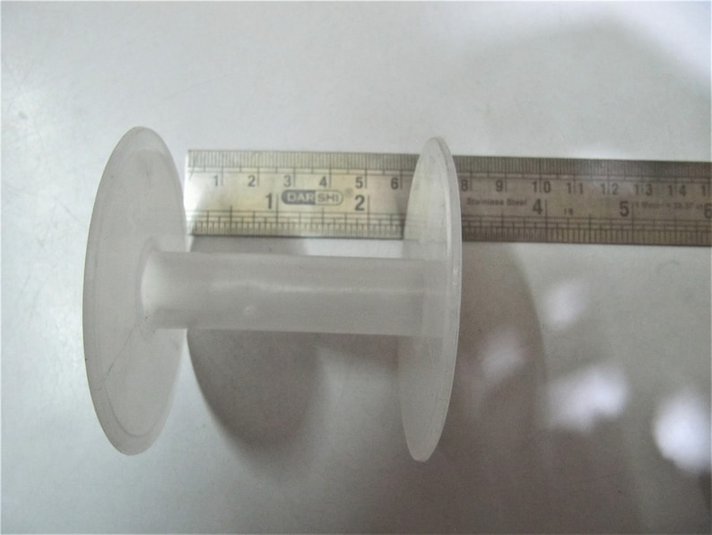 May include: A white plastic spool with a center hole, measuring approximately 6 inches in diameter.