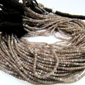 May include: A strand of light pink and gray gemstone beads. The beads are faceted and have a shimmery finish. The strand is approximately 16 inches long and is perfect for making jewelry.
