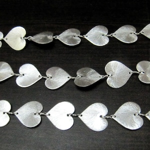May include: A silver chain necklace with heart-shaped links. The chain is made of small, delicate hearts that are connected together.