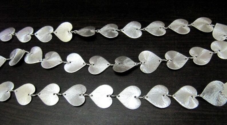 May include: A silver chain necklace with heart-shaped links. The chain is made of small, delicate hearts that are connected together.