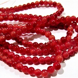 May include: A strand of red gemstone beads. The beads are round and have a smooth, polished finish.