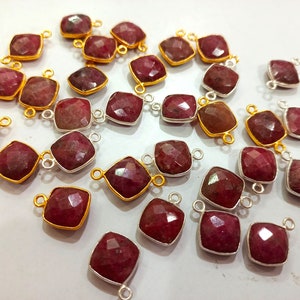 May include: A collection of square-cut, faceted ruby gemstone pendants. Some are set in gold-colored metal, others in silver-colored metal. Each pendant has a small loop for attaching to a chain or other jewelry component.