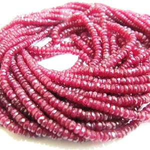 Puede incluir: Una hebra de cuentas de rubí rojo oscuro, cada cuenta está facetada y tiene una forma ligeramente irregular. Las cuentas están enhebradas para formar un collar largo.