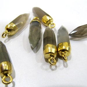 May include: Six grey gemstone pendants with gold-toned metal caps and loops. The gemstones are faceted and have a pointed shape.