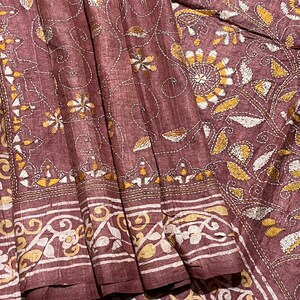 May include: A maroon silk saree with intricate white and gold embroidery. The embroidery features floral and paisley patterns.