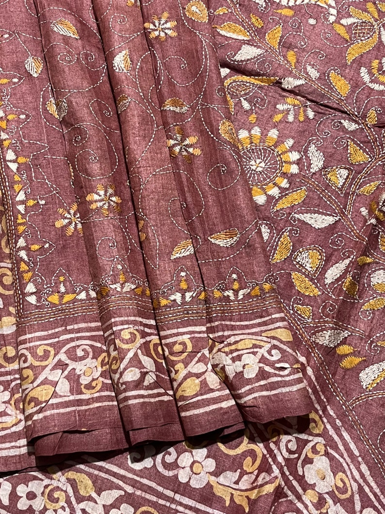 May include: A maroon silk saree with intricate white and gold embroidery. The embroidery features floral and paisley patterns.