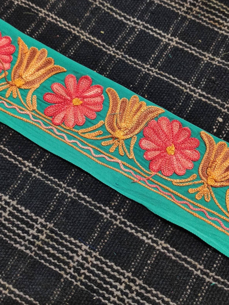May include: Teal fabric trim with embroidered flowers and stylised tulips in shades of red, orange, and yellow.