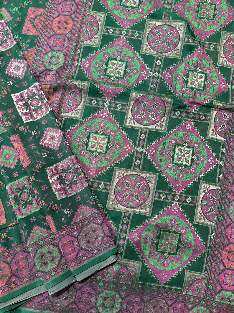 May include: Green fabric with a repeating pattern of pink and green squares and circles. The fabric has a subtle shimmer.