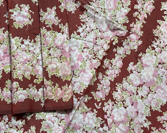 Könnte beinhalten: Blumenstoff mit einem sich wiederholenden Muster aus rosa und weißen Blumen mit grünen Blättern auf einem dunkelroten Hintergrund. Der Stoff ist an manchen Stellen gefaltet und zeigt die Kontinuität des Musters. Ideal für Nähprojekte.