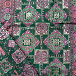May include: Green fabric with a repeating pattern of pink and silver squares and circles. The fabric has a subtle sheen.