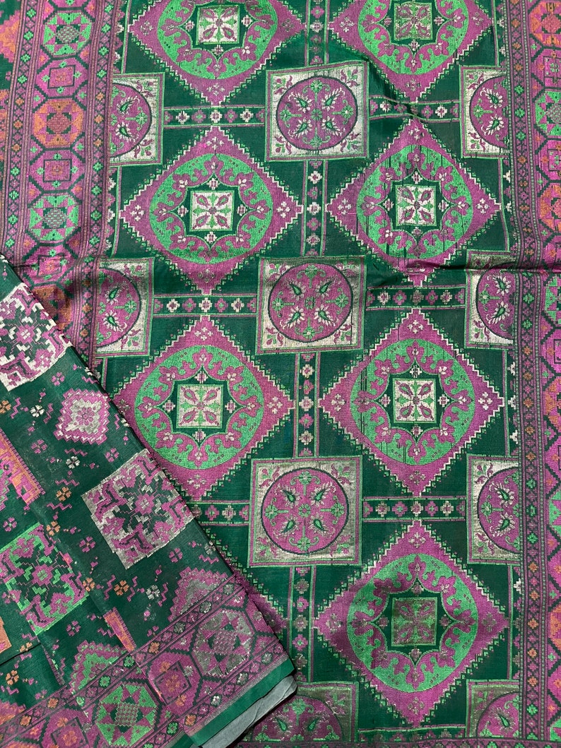 May include: Green fabric with a repeating pattern of pink and silver squares and circles. The fabric has a subtle sheen.